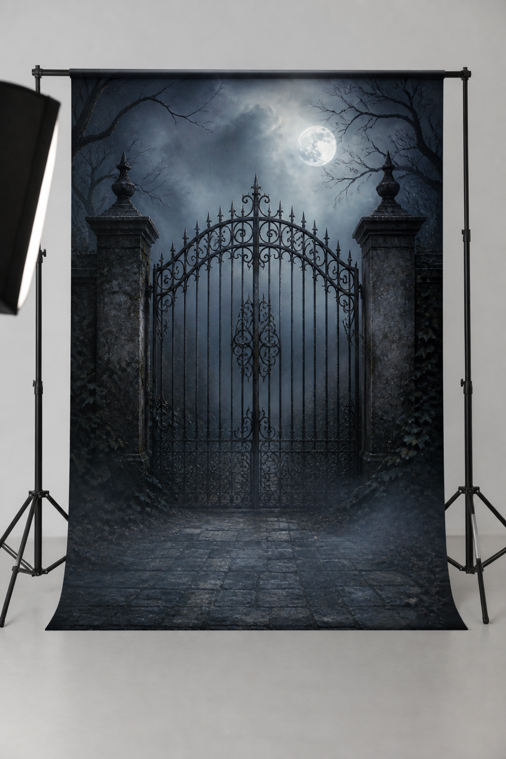 Moonlit iron gate and misty path photography backdrop printed on matte microfiber, shown hanging on a backdrop stand in a studio