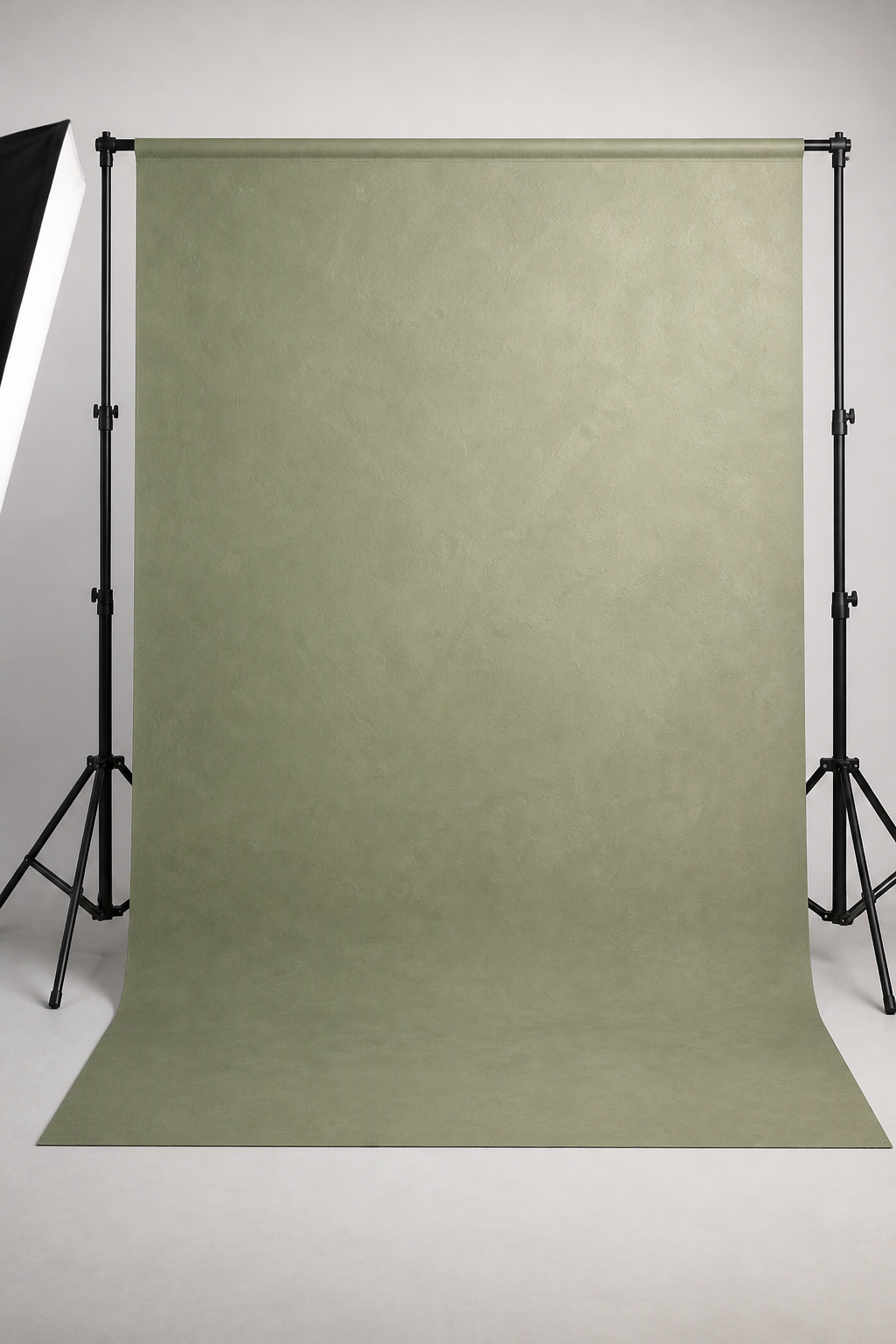 Soft sage studio sweep photography backdrop printed on matte microfiber, shown hanging on a backdrop stand in a studio
