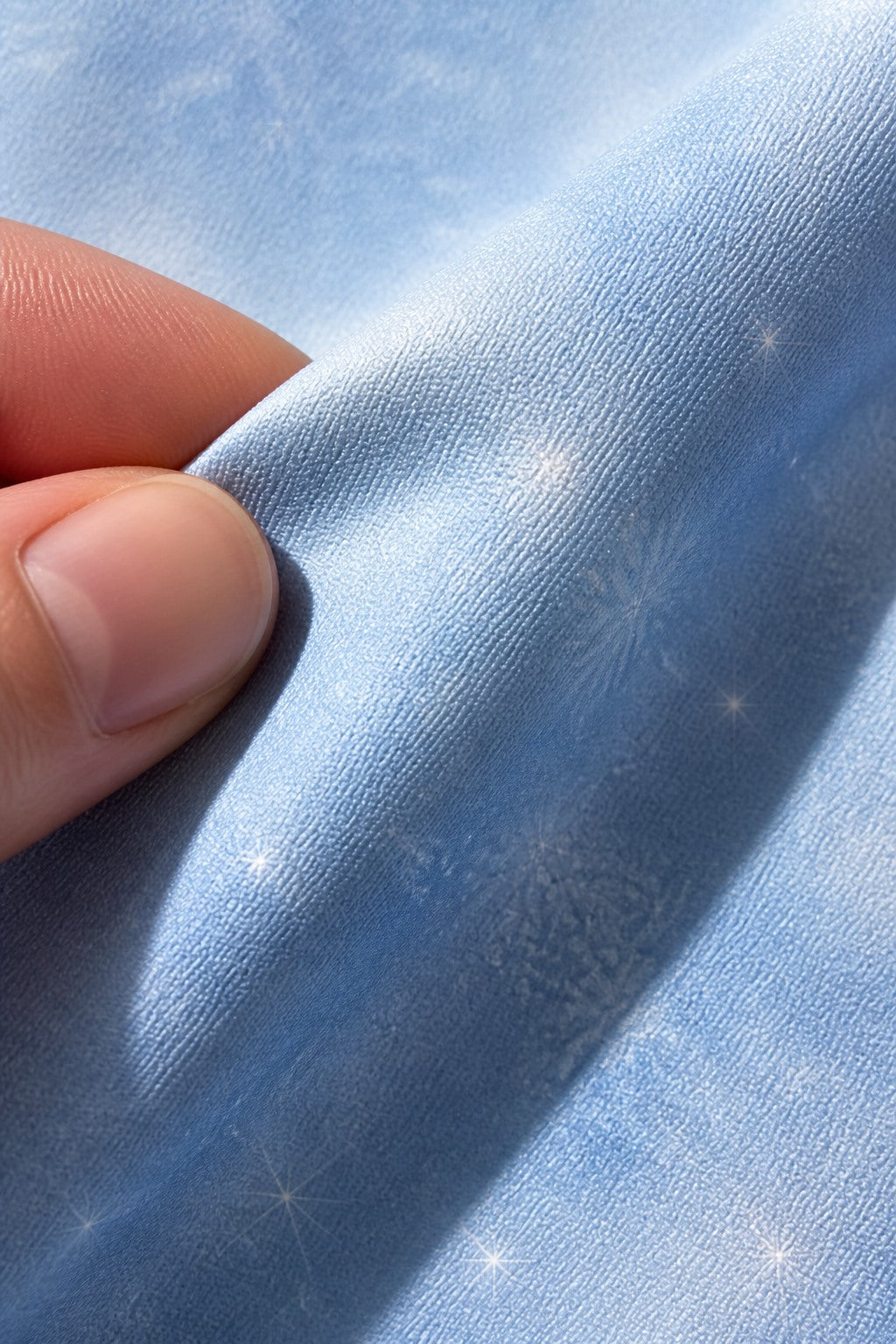 Close-up of the short-pile wrinkle-resistant fabric texture of the Icy Blue Snow Sparkle photography backdrop, held at the corner