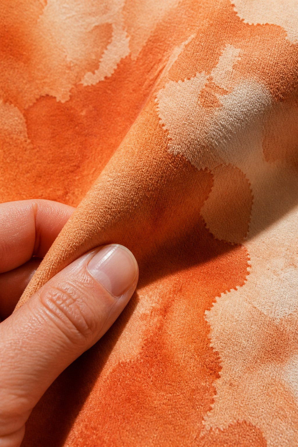 Close-up of the short-pile wrinkle-resistant fabric texture of the Terracotta Ink Blotch photography backdrop, held at the corner