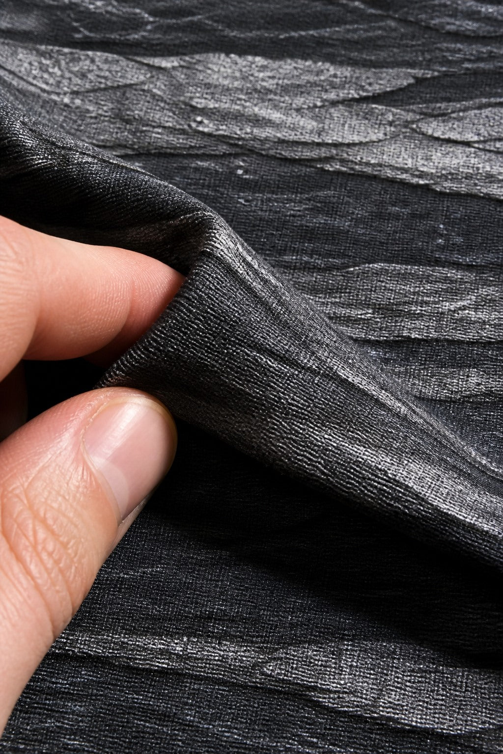 Close-up of the short-pile wrinkle-resistant fabric texture of the Charcoal Rock Strata photography backdrop, held at the corner
