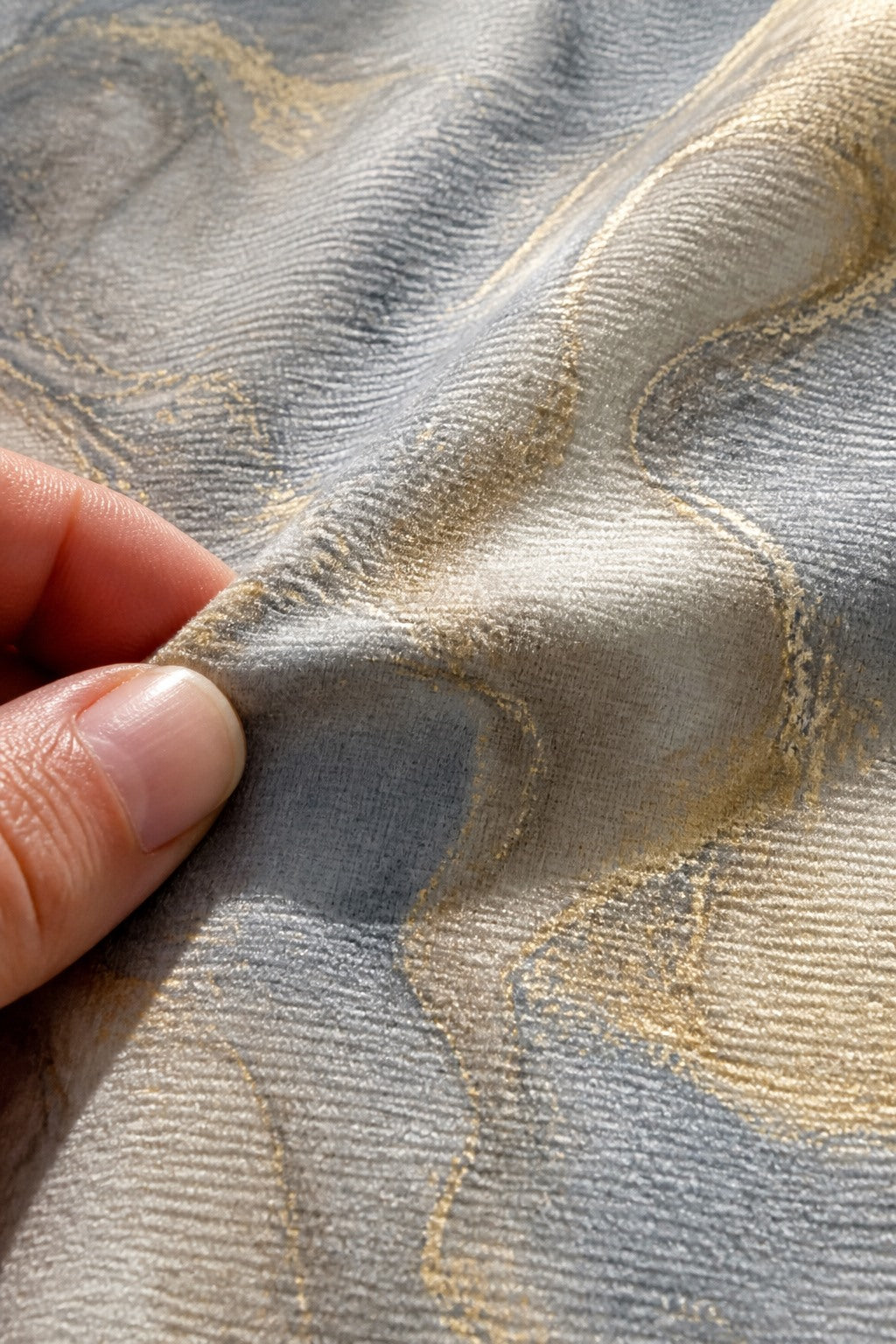 Close-up of the short-pile wrinkle-resistant fabric texture of the Warm Gray Marble photography backdrop, held at the corner